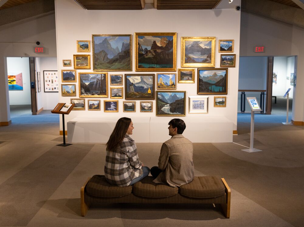 Two people sit on a bench in front of an art gallery in the Whyte Museum.
